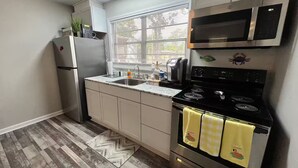 Eine kleine Küche mit Kühlschrank, Mikrowelle, Herd und Spüle.