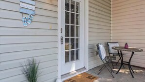A house entrance with a white door, a small porch with a table and chairs, and a welcome sign on the wall. - Entire home in Gulfport, Mississippi (Gautier)