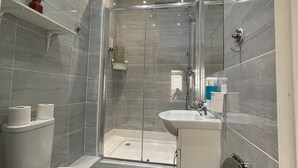 Un baño moderno con ducha de vidrio, inodoro y lavamanos.