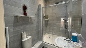 Un baño moderno con cabina de ducha de vidrio, inodoro y lavabo con espejo.