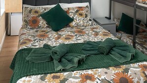 Un dormitorio con cama, mesita de noche, escritorio pequeño, microondas y lavamanos.