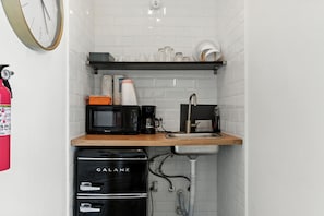 Et lille tekøkken med mikroovn, kaffemaskine og vask.