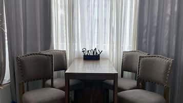 Un espace repas comprenant une table rectangulaire et quatre chaises rembourrées dont les dossiers sont décorés de boutons.