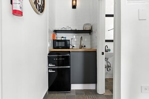 Een kleine keuken met een zwarte koelkast, een magnetron en een spoelbak.