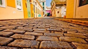 A cobblestone street with buildings on either side. - Puerto Rico Gem 2BR Walk to Beach Wi-Fi (Condado)