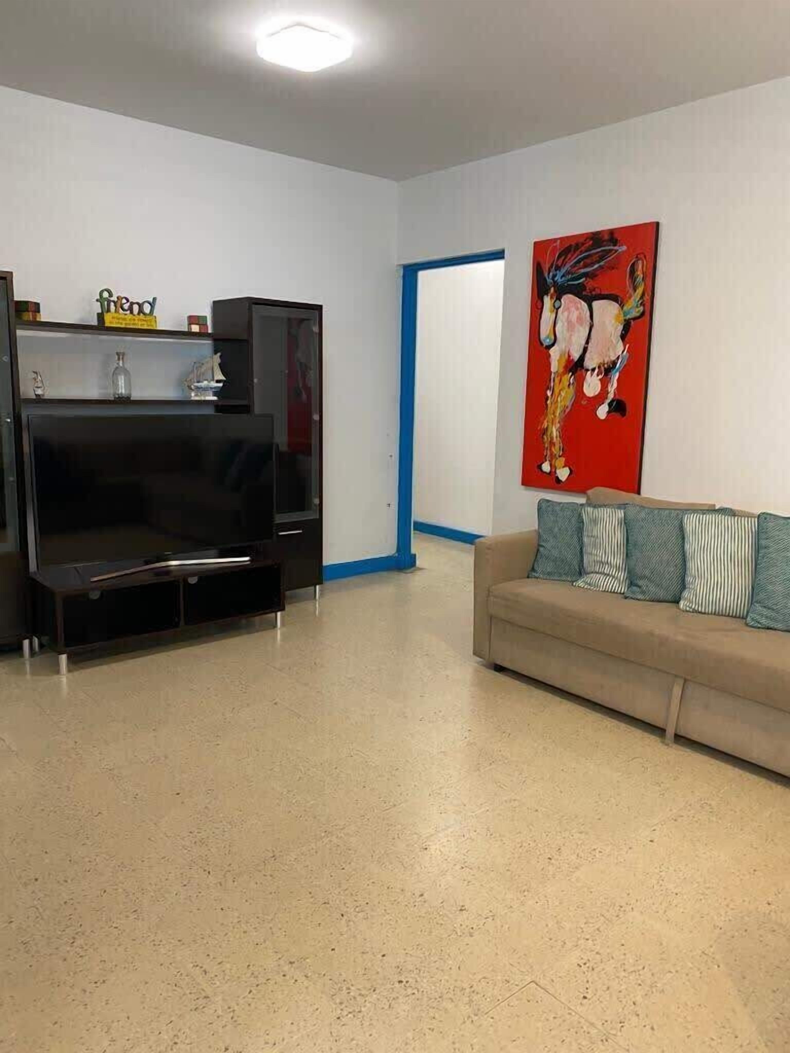 A living room with a TV, a sofa, and a painting on the wall.