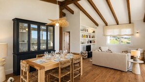 A dining area with a wooden table set for six, a black cabinet with glass doors, and a woven chair. - Villa Inés · Llanes · Single-story house with a garden (Cardoso (Llanes))