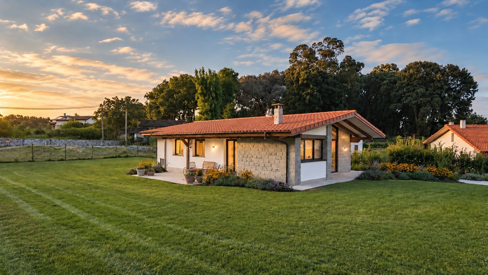 A single-story house with a red-tiled roof, a stone facade, and a well-maintained lawn.