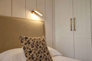 A neatly made bed with a floral pillow, a headboard, and a bedside lamp. - Villa Inés · Llanes · Single-story house with a garden (Cardoso (Llanes))