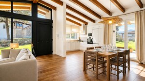 A spacious living area with a dining table and chairs, a sofa, and a kitchen in the background. - Villa Inés · Llanes · Single-story house with a garden (Cardoso (Llanes))