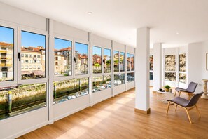 A spacious room with large windows, wooden flooring, and a view of a cityscape. - Llanes Downtown Port View Apartment - Vega 2 (Llanes)