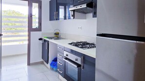 A modern kitchen with a stainless steel refrigerator, a gas stove, and dark blue cabinets.