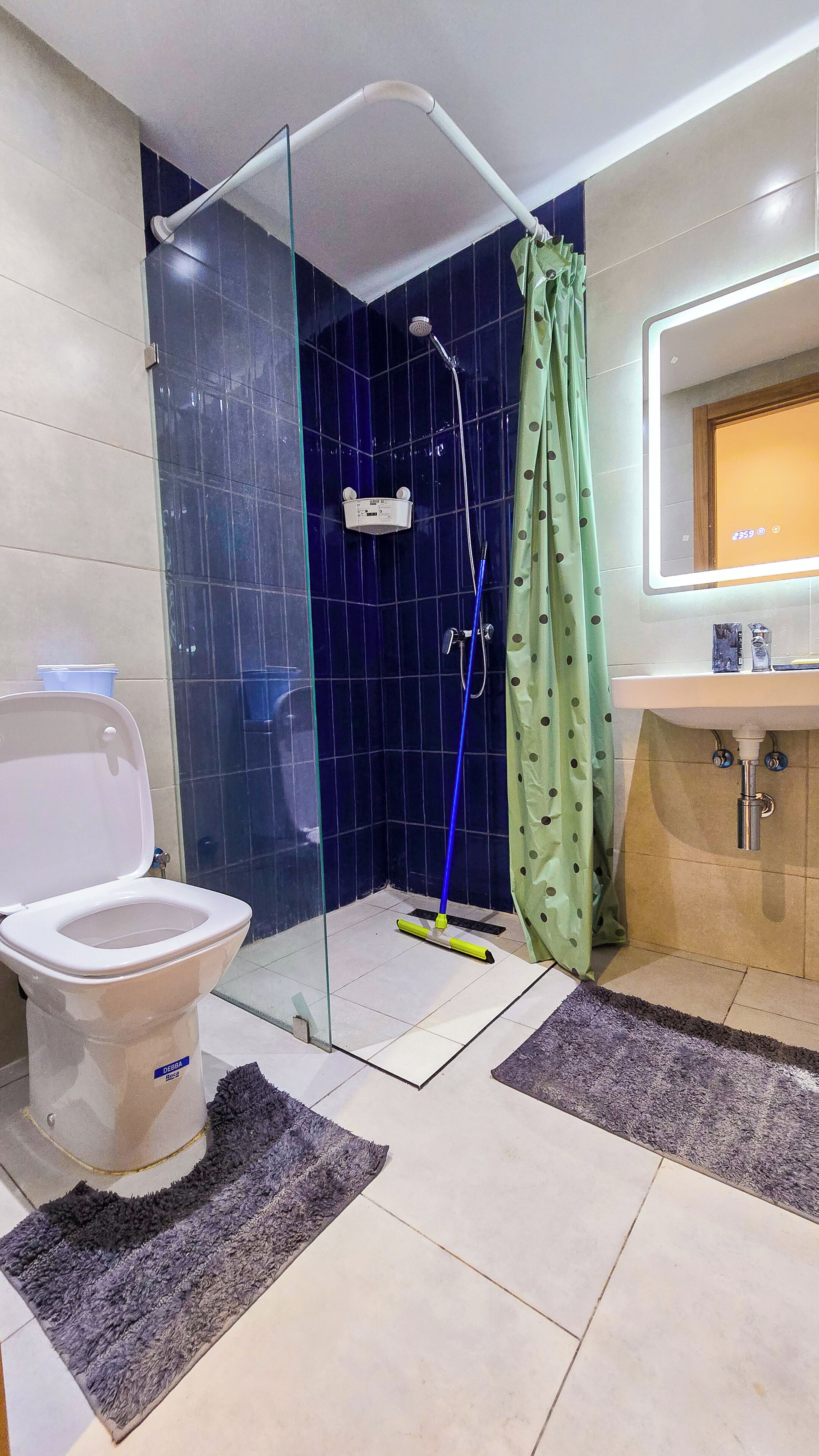 Een badkamer met een douche met glazen wand, toilet en een wastafel met spiegel.
