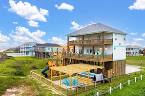 Ein mehrstöckiges Gebäude mit Balkon, Pool und einer Holzterrasse mit St ühlen.