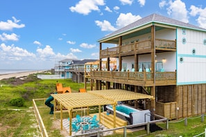 Um edifício de vários andares com um deck de madeira, área de estar externa e piscina.