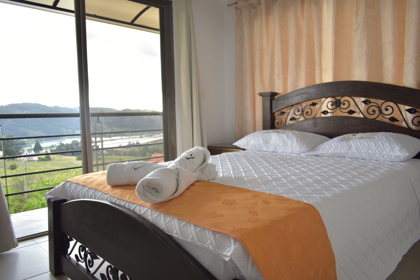 A hotel room with a bed, a view of a lake, and a balcony.