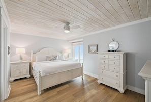 Ein Schlafzimmer mit Bett, Nachttischen, Kommode und Deckenventilator.