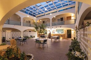 A spacious indoor atrium with a high ceiling, multiple seating areas, and a central plant arrangement.