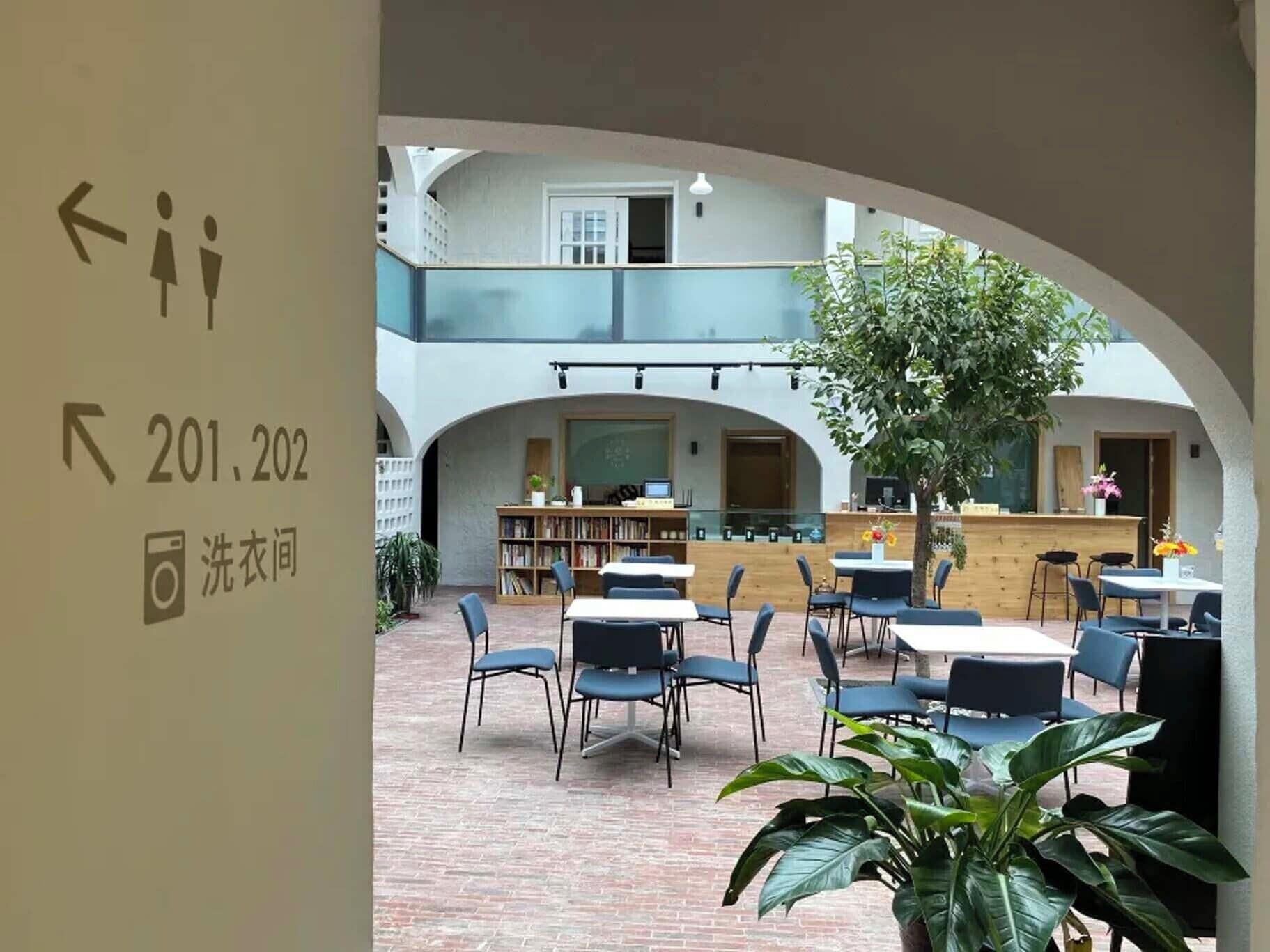 A courtyard with outdoor seating, a bookshelf, and a chalkboard.