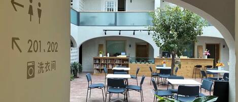A courtyard with outdoor seating, a bookshelf, and a chalkboard.