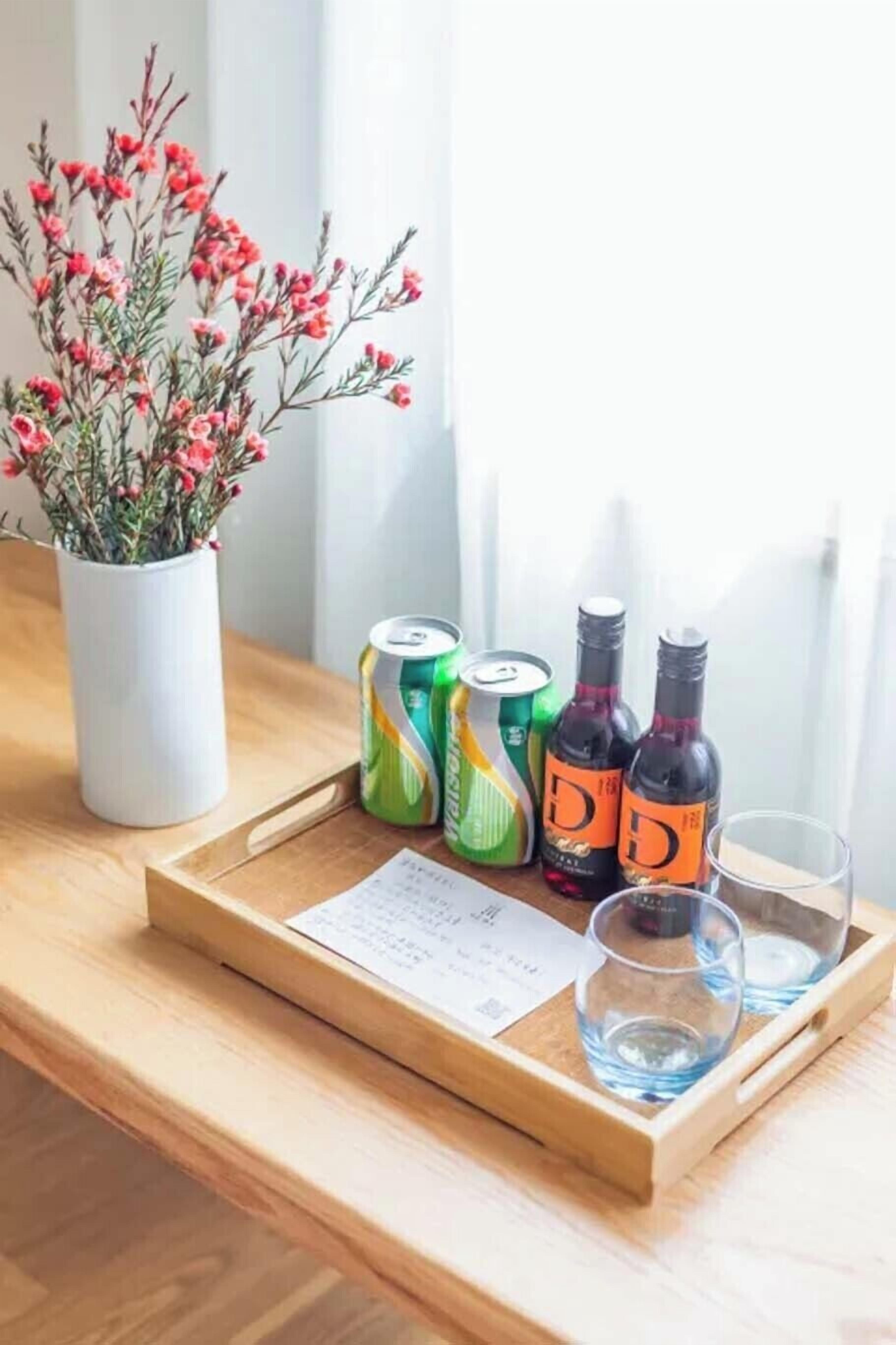 Une table en bois sur laquelle se trouve un plateau contenant deux canettes, deux bouteilles et deux verres.