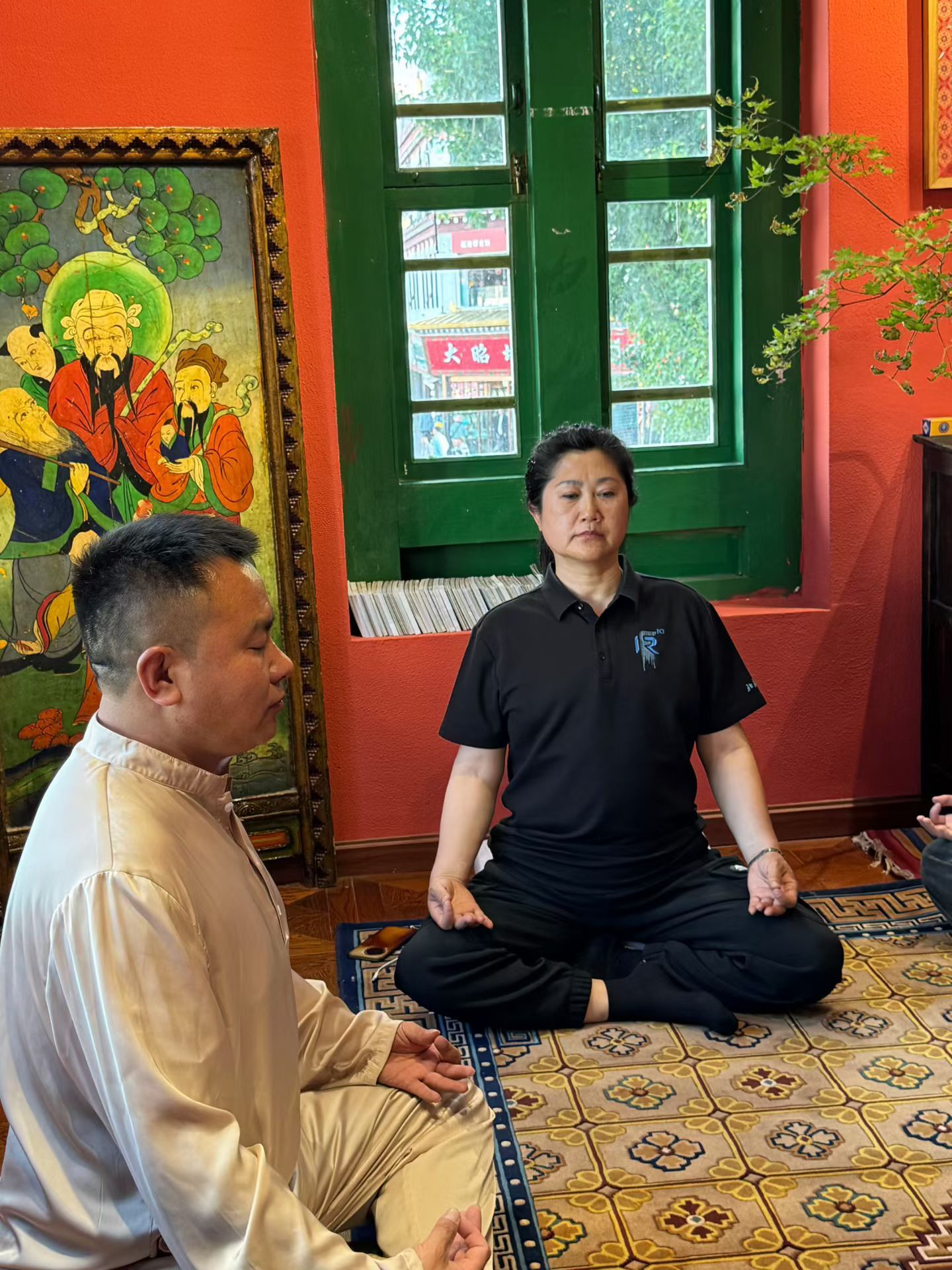 Une pièce décorée d’un tableau de style asiatique traditionnel, avec une fenêtre verte et un sol à motifs.