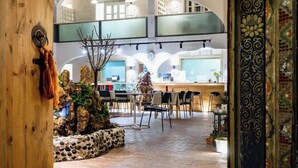 An indoor dining area with a rustic wooden floor, stone walls, and a central seating arrangement. - TRANQUIL HOUSE (Lhasa)