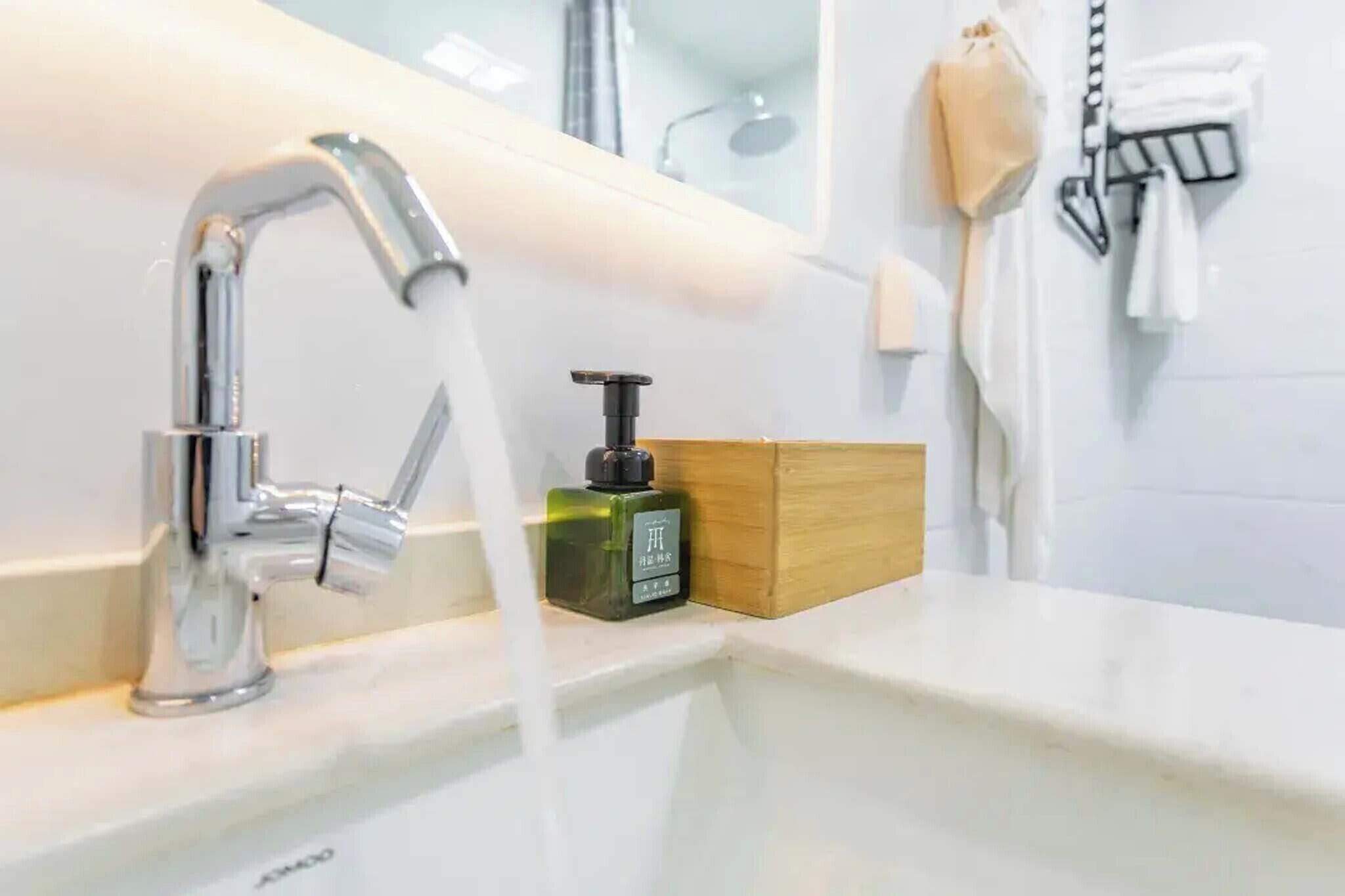 A bathroom with a chrome faucet, a soap dispenser, and a towel rack.