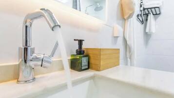 A bathroom with a chrome faucet, a soap dispenser, and a towel rack.
