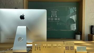 A wooden desk with a MacBook, a MacBook stand, and a framed sign with Chinese characters.
