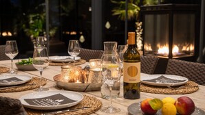 A table set for dining with wine glasses, plates, and a bottle of wine. - Beautiful home in Portocolom (Portocolom)