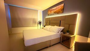 Une chambre moderne avec un grand lit, une table de chevet avec une lampe et une œuvre d’art accrochée au mur.