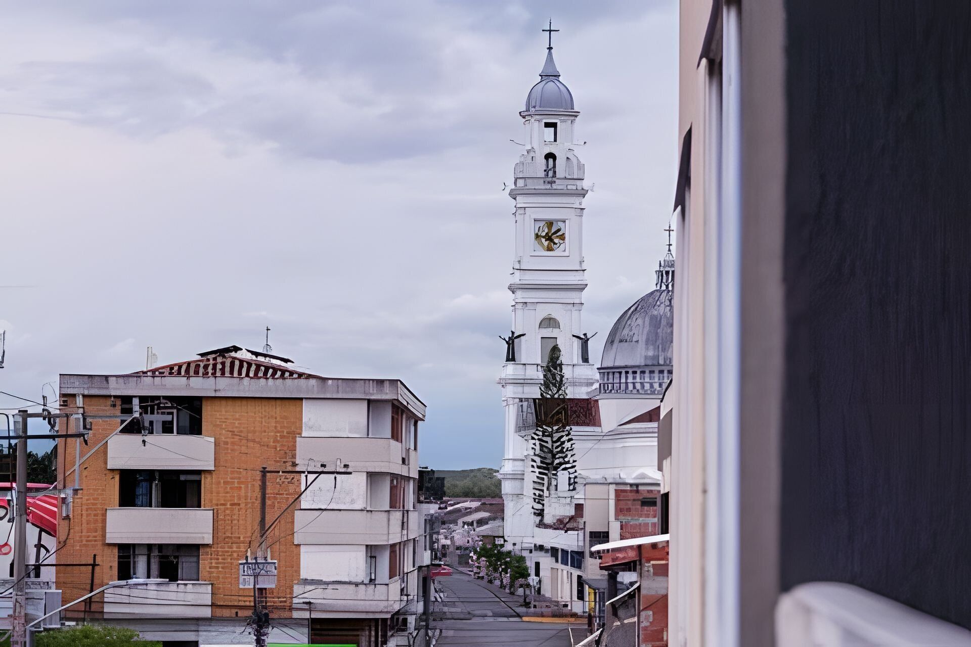 A view of a town with a prominent white clock tower and a dome structure.