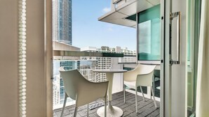 Ein Balkon mit Tisch und Stühlen, einer Glastür und Blick auf hohe Gebäude.