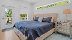 A bedroom with a large bed, a nightstand with a mirror, and a window with a view of trees. - Peaceful Retreat, Close to the Beach (Pass Christian)