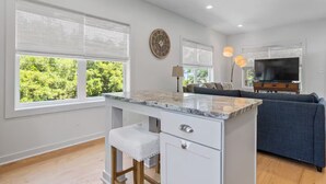 A modern kitchen with a marble countertop, a built-in bench, and a wall-mounted clock. - Peaceful Retreat, Close to the Beach (Pass Christian)