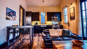 A compact living space with a kitchenette, a dining area with a table and chairs, and a seating area with a sofa and a coffee table. - The Penthouse Suite - South Main Escape (Buena Vista)