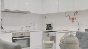 Eine moderne Küche mit weißen Schränken, einem Bosch Geschirrspüler, einer Kaffeemaschine und einem Gasherd.