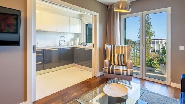 Un apartament modern amb cuina, zona de menjador amb taula de vidre, i un balcó amb vistes.