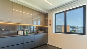 Eine moderne Küche mit dunklen Schränken, einer Granitabdeckung und einem Fenster mit Blick auf die Stadt.