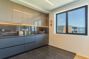 A modern kitchen with dark cabinetry, a granite countertop, and a window with a city view. - Renala III, by Pausa Holiday Rentals (Funchal)