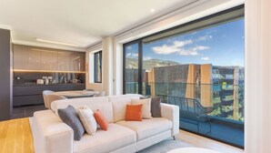 Ein modernes Wohnzimmer mit großem Fenster, einer Couch und einem Essbereich.