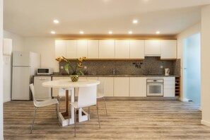 Eine moderne Küche mit weißen Schränken, einer Arbeitsplatte aus Granit, einem eingebauten Backofen und einem Essbereich mit Tisch und Stühlen.