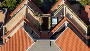 Vista aérea de un edificio con un patio central, rodeado de balcones escalonados con techos de tejas rojas.