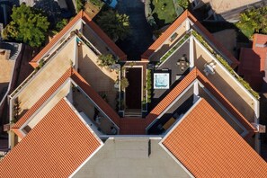 Eine Luftaufnahme eines Gebäudes mit einem zentralen Innenhof, umgeben von terrassenförmigen Balkonen mit roten Ziegeldächern.