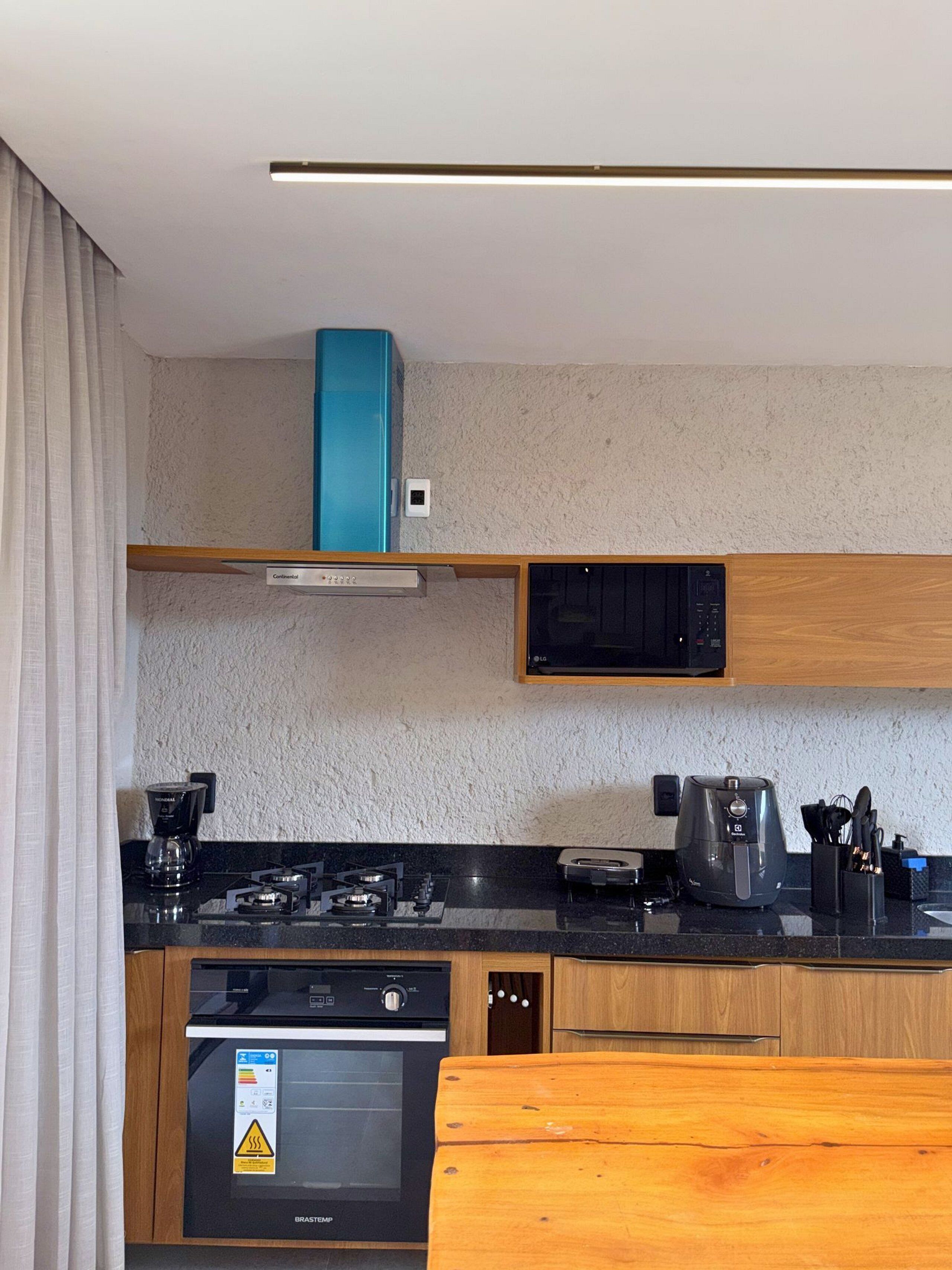 A compact kitchen with a gas stove, coffee maker, microwave, and a built-in oven.