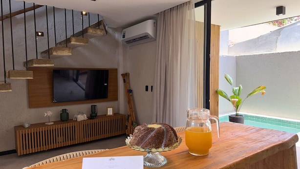 A modern living room with a TV, wooden furniture, a staircase, and a view of the outdoors. - MHV Milagres - Nani Villas Boutique (São Miguel dos Milagres)