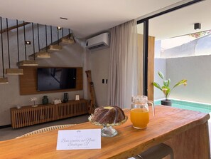 Een moderne woonkamer met een televisie, houten meubels, een trap en uitzicht op de omgeving.