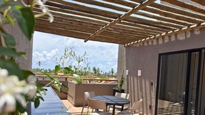 An outdoor patio with a table and chairs, a pergola, and a view of palm trees. - MHV Milagres - Nani Villas Boutique (São Miguel dos Milagres)