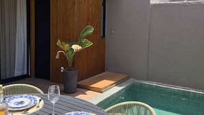 A patio with a table set for dining, a small pool, and a potted plant. - MHV Milagres - Nani Villas Boutique (São Miguel dos Milagres)